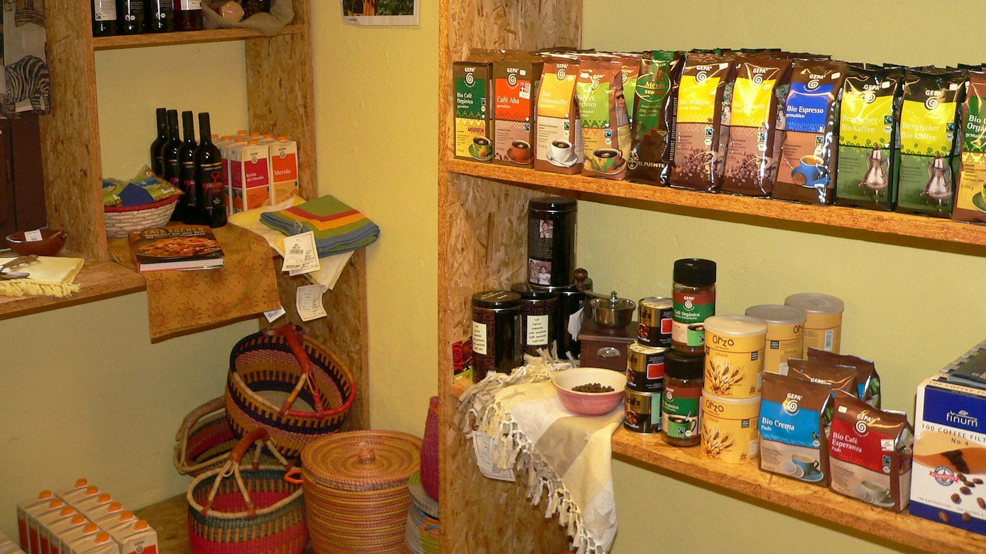 Im Regal stehen Flaschen, Packungen und weitere fair gehandelte Produkte.