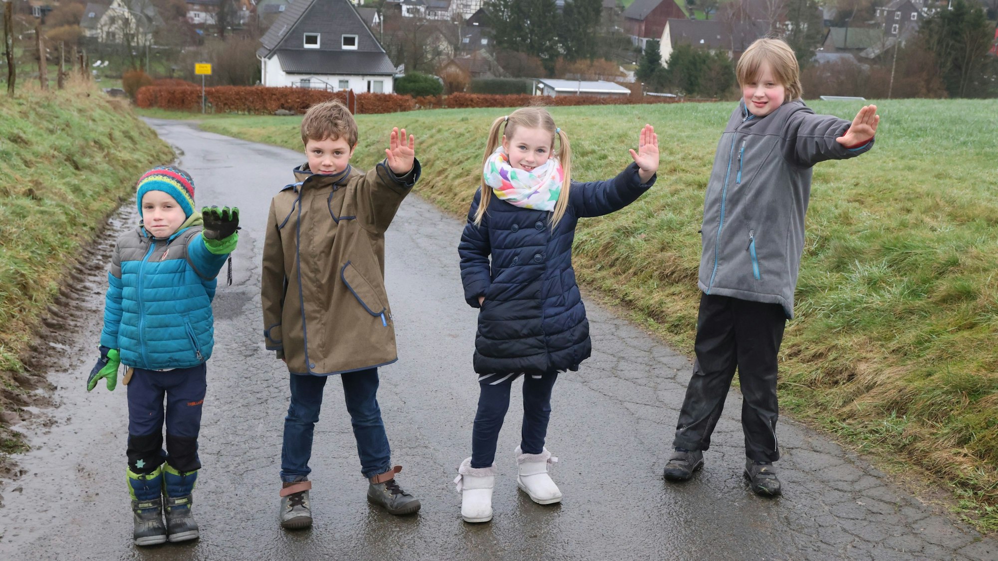 Man sieht die Kinder, wie sie nebeneinander auf dem Feldweg stehen, sie strecken jeweils ihre linke Hand als Stop-Signal nach vorne.