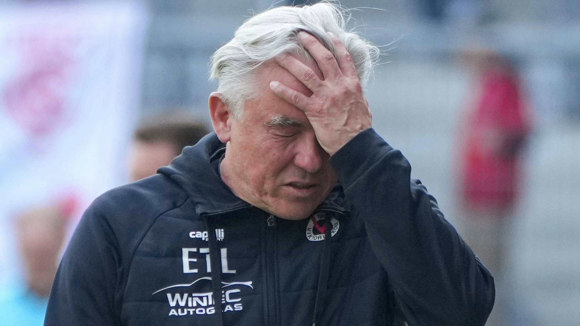 Ein Fußballtrainer fasst sich entgeistert an den Kopf.