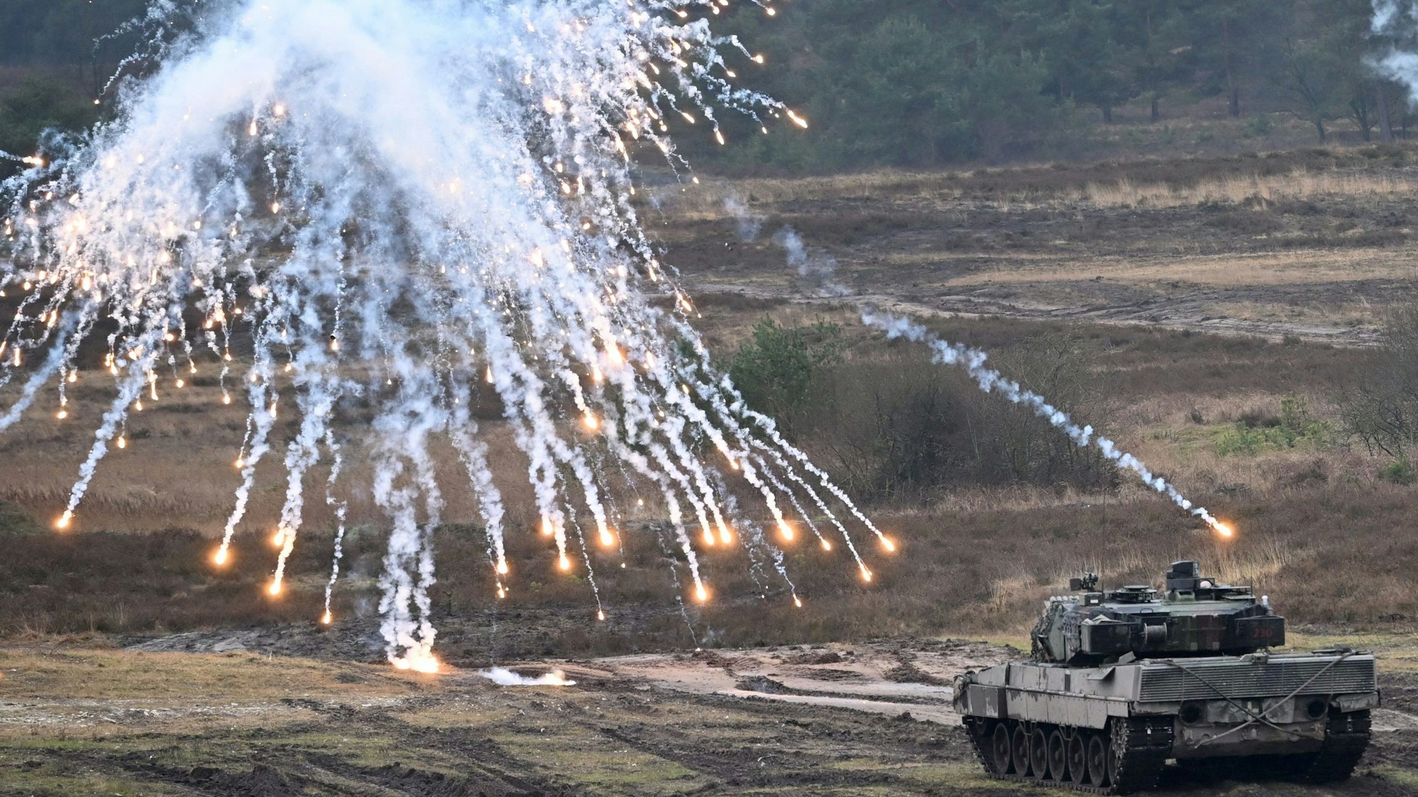 Ein Panzer vom Typ Leopard 2A6 schießt bei einer Übung auf freiem Gelände mit Rauchgranaten.