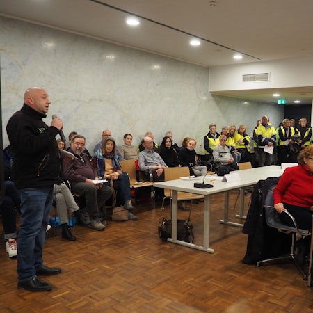 Tibor Schady warb in der Sitzung des Erftstädter Stadtrats um Unterstützung für das Spendenlager. Im Hintergrund sind zahlreiche Helfer zu sehen.