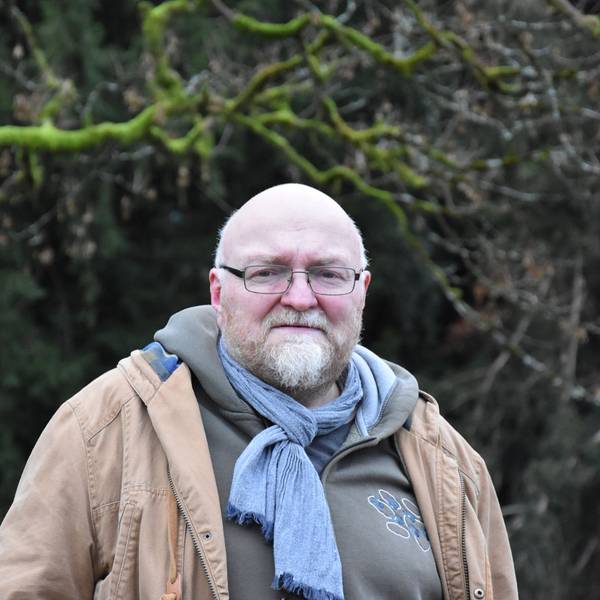 Man sieht Pedall vor einem Wald im Hintergrund stehen. Er schaut in die Kamera.