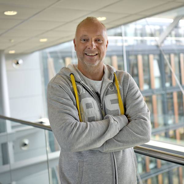 Frank Buschmann lacht in einem grauen Pullover.
