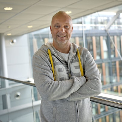 Frank Buschmann lacht in einem grauen Pullover.