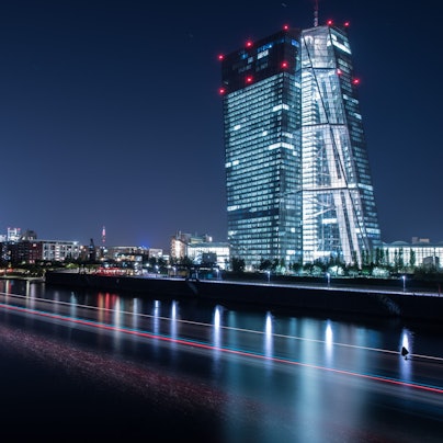 Die Lichter der Europäischen Zentralbank (EZB) leuchten am in Frankfurt am Main, während ein auf dem Main vorbeifahrendes Schiff Lichtspuren durch die Aufnahme zieh