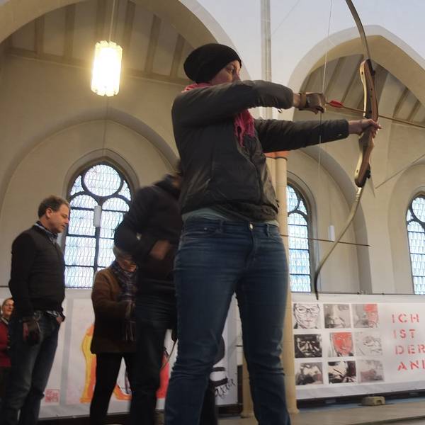 Frau, die Pfeil und Bogen in der Hand hält und auf etwas zielt