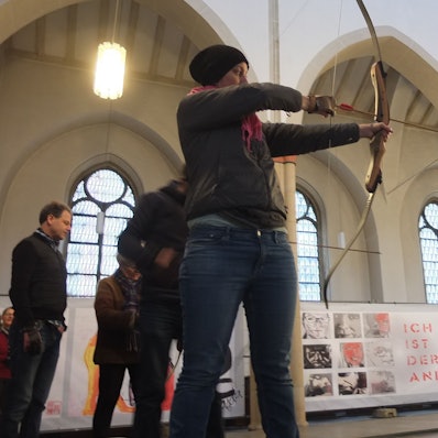 Frau, die Pfeil und Bogen in der Hand hält und auf etwas zielt