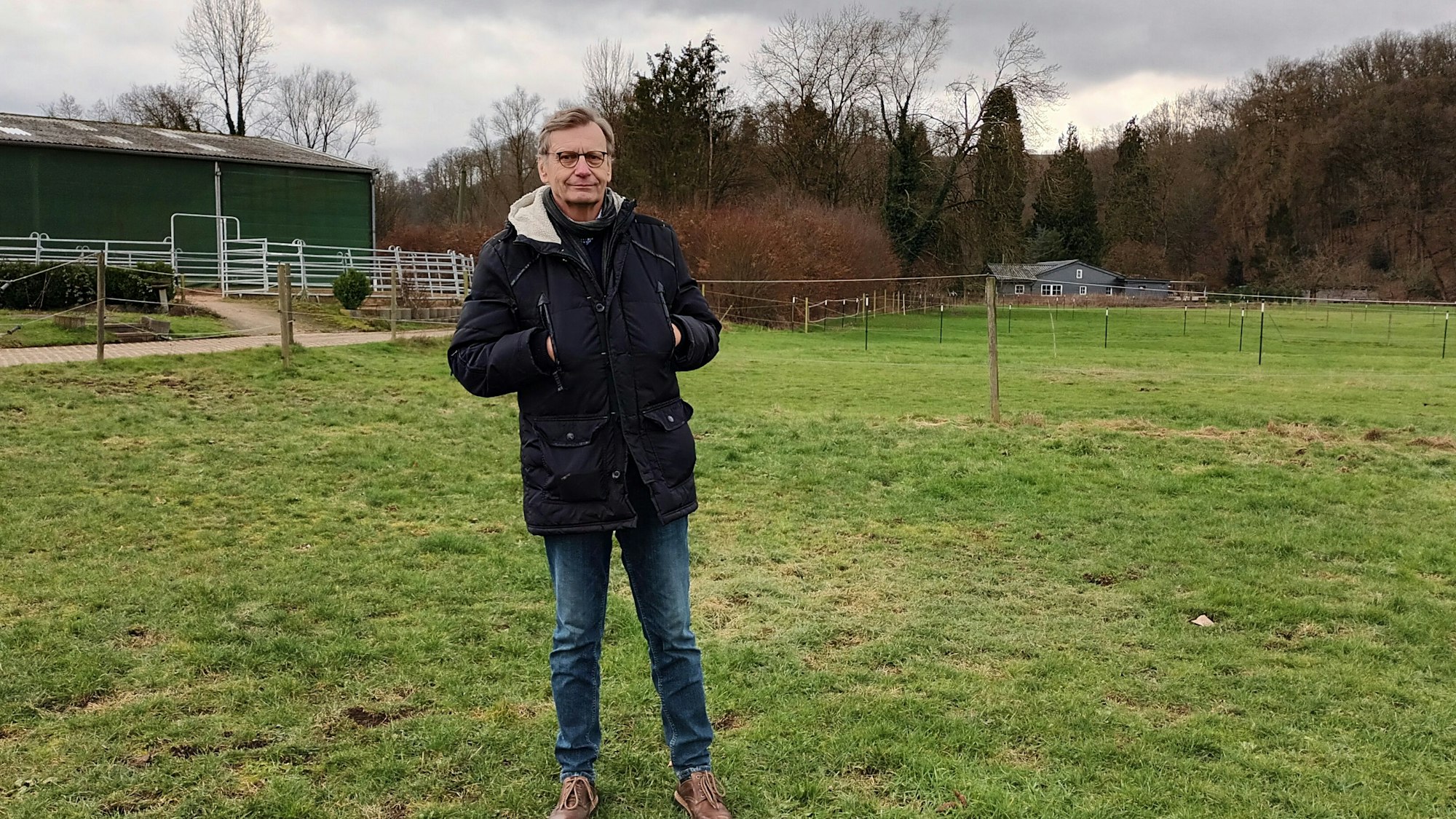 Dr. Jacek Gawda steht auf einer Wiese, die Hände in den Taschen seines Parka.