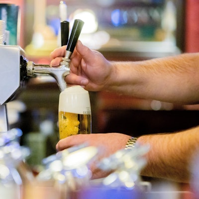Ein Kneipenwirt zapft in einer Gaststätte Bier.