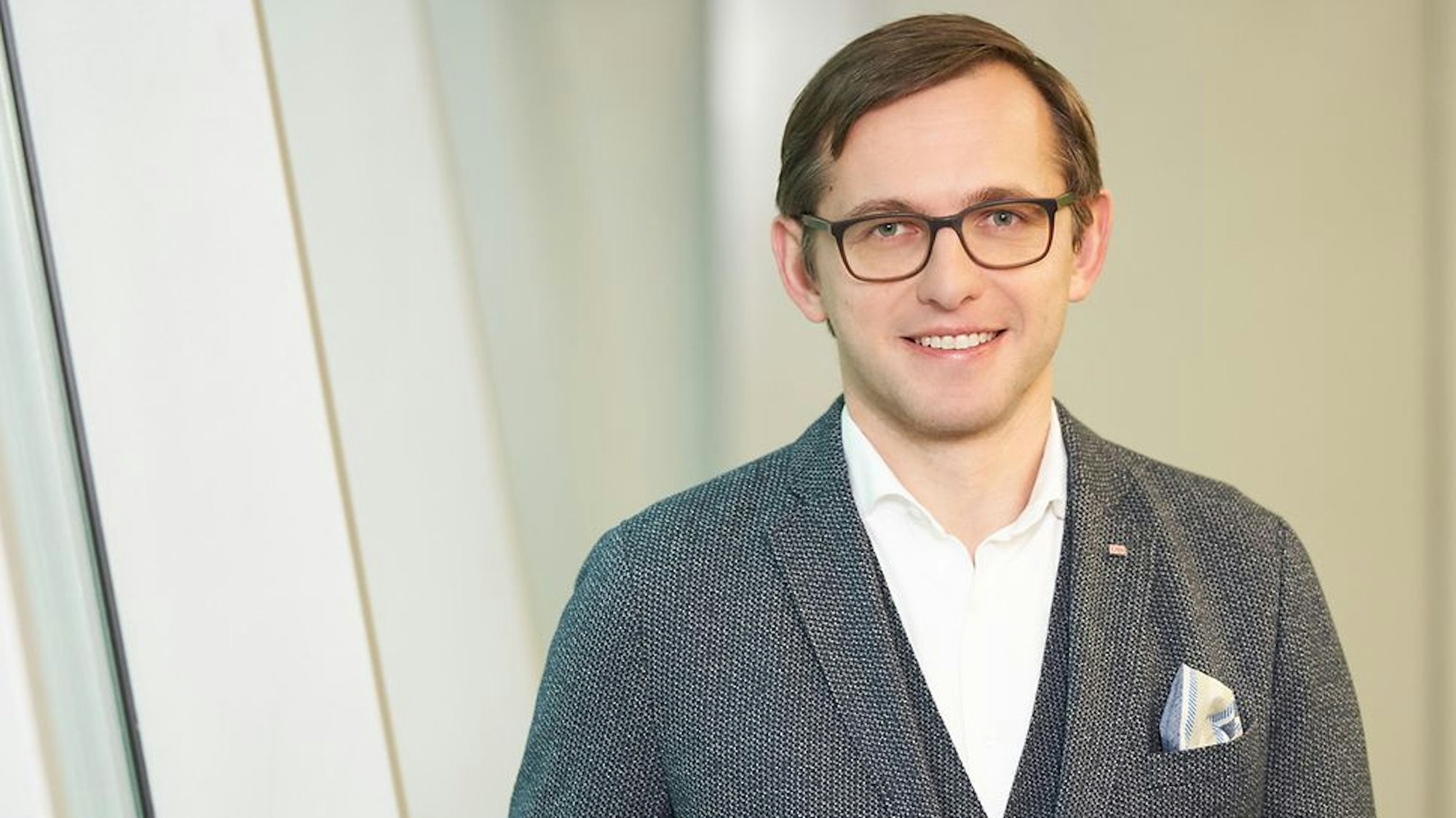Philipp Nagl, Vorstand der DB Netz AG, trägt ein weißes Hemd und ein graues Jackett und eine Brille.