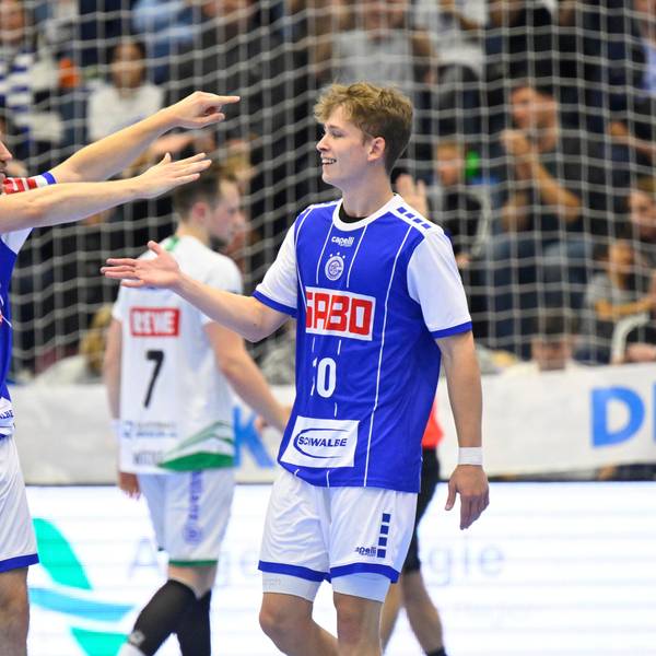 Dominik Mappes, Handballspieler des VfL Gummersbach, läuft bei einem Spiel mit ausgebreiteten Fänden auf seinen Mannschaftskollegen Finn Schroven zu.
