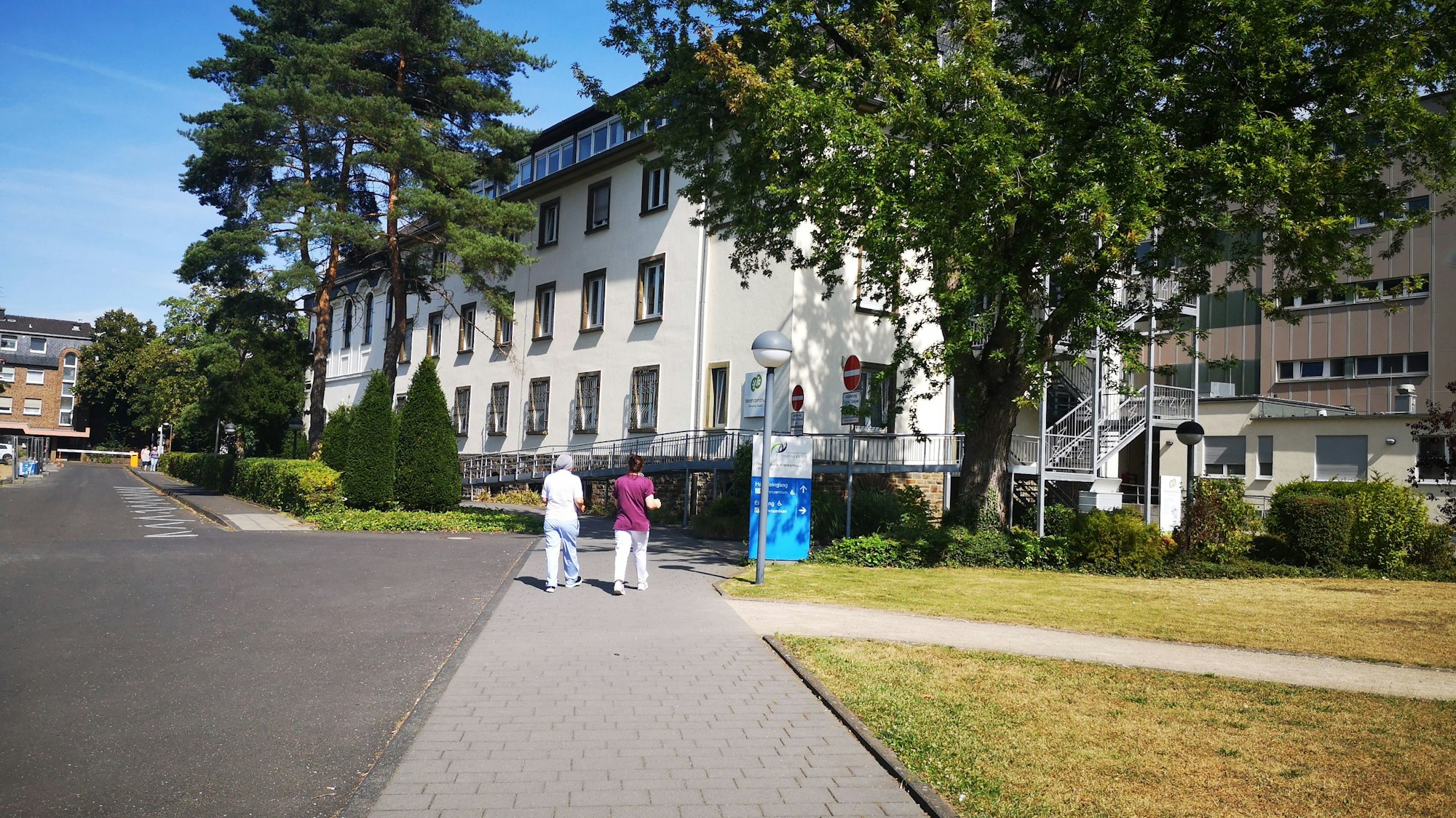 Das Foto zeigt das Krankenhaus Wesseling von außen. Zwei Frauen gehen Richtung Eingang.