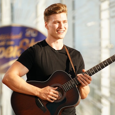 Nico Grund steht mit seiner Gitarre vor dem Logo von Deutschland sucht den Superstar.