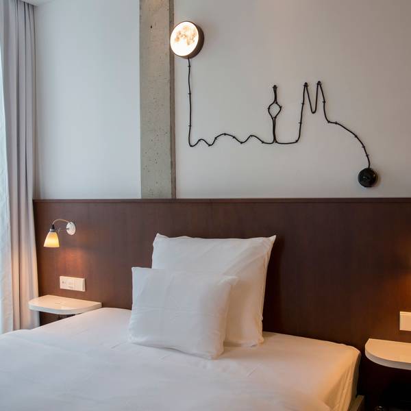 Ein Hotelzimmer mit einer Lichtleiste in Form des Köln-Panoramas über dem Bett
