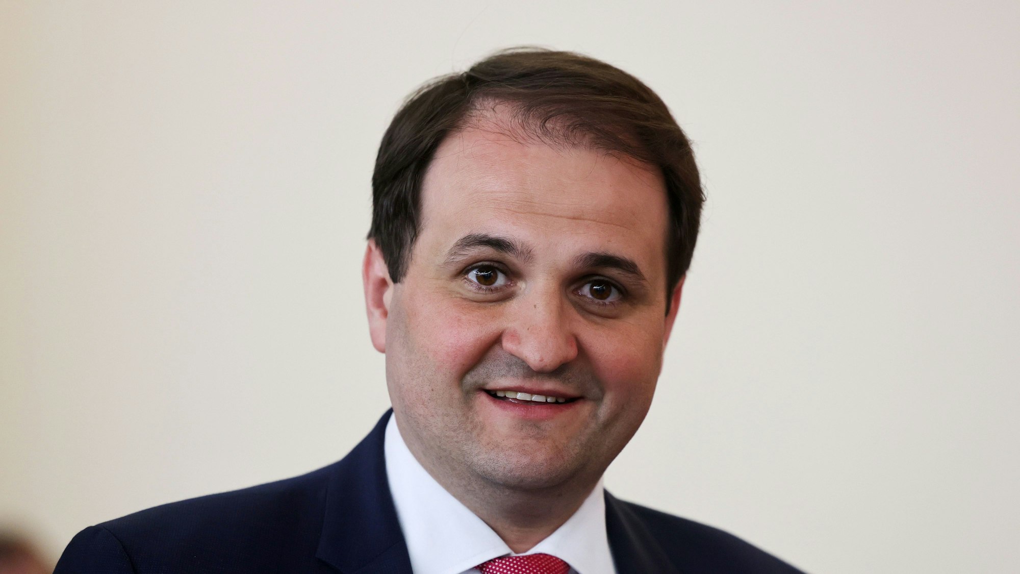 Nathanael Liminski (CDU), Chef der Staatskanzlei des Landes Nordrhein-Westfalen, steht vor einer weißen Wand. Er trägt einen blauen Anzug.