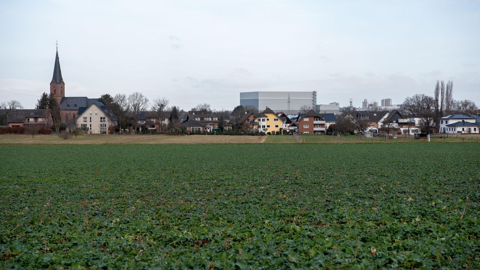 Gebäude des Siedlungsschwerpunkts Firmenich-Obergartzem stehen im Hintergrund vor einem Feld