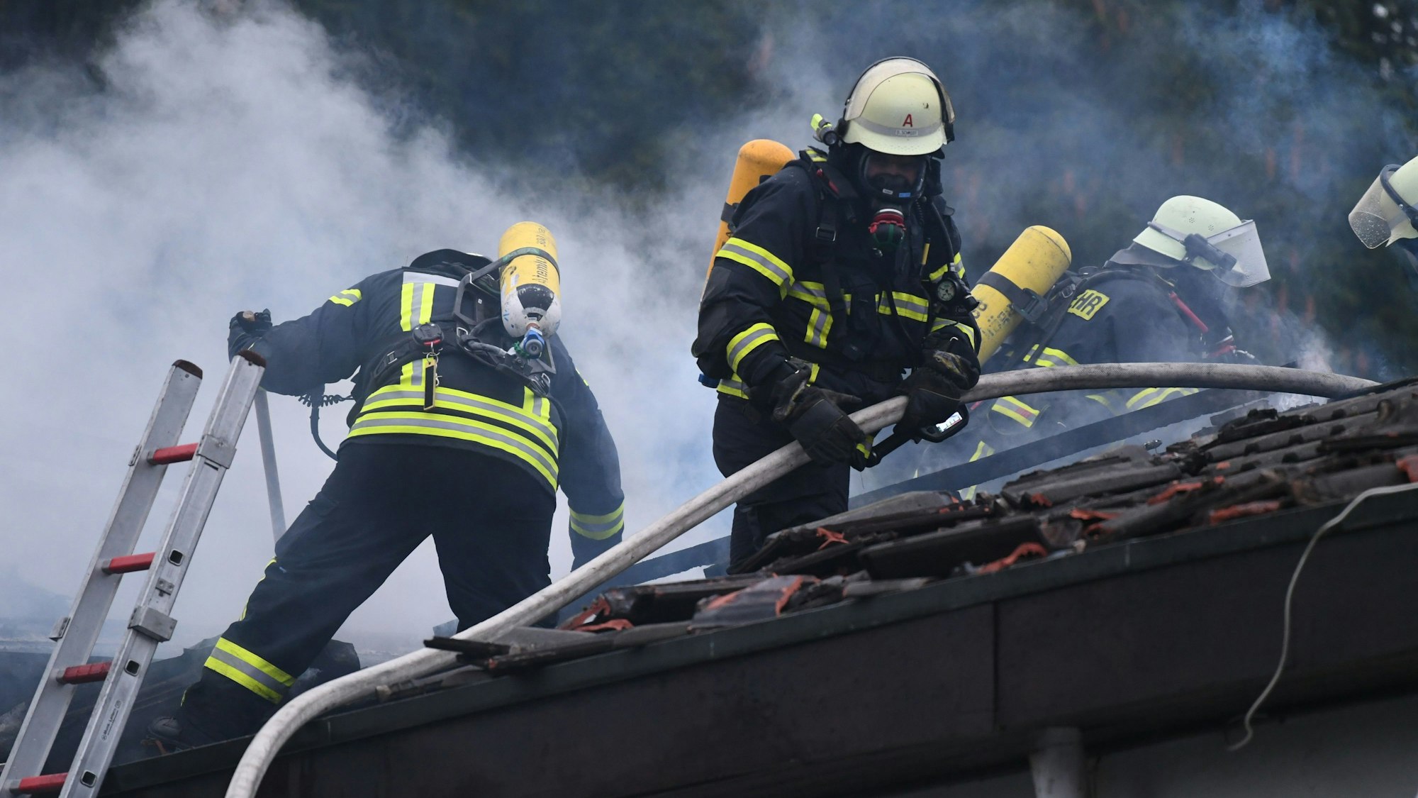 Es sind mehrere Einsatzkräfte auf dem Dach des Hauses zu sehen.