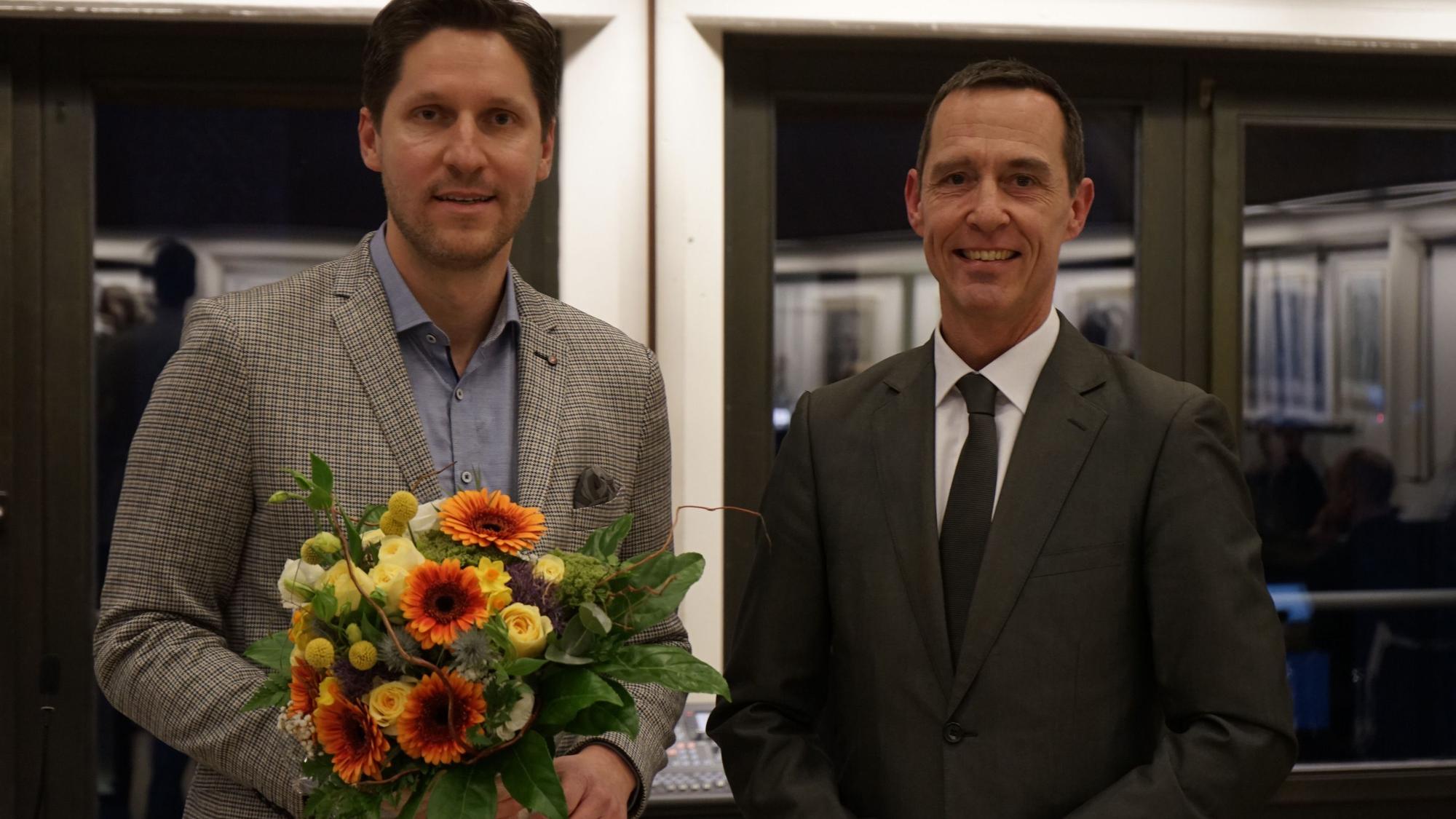 Dominik Laufs steht mit Blumenstrauß neben Kerpens Bürgermeister Dieter Spürck.