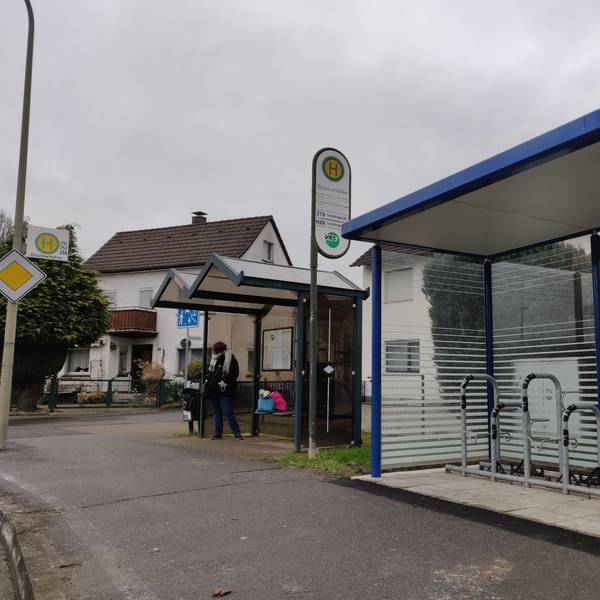 An der Bushaltestelle in Büscherhöfen steht neben dem Wartehäuschen für Busfahrgäste ein neuer blauer verglaster Unterstand mit Schlossbügeln für Radfahrer.