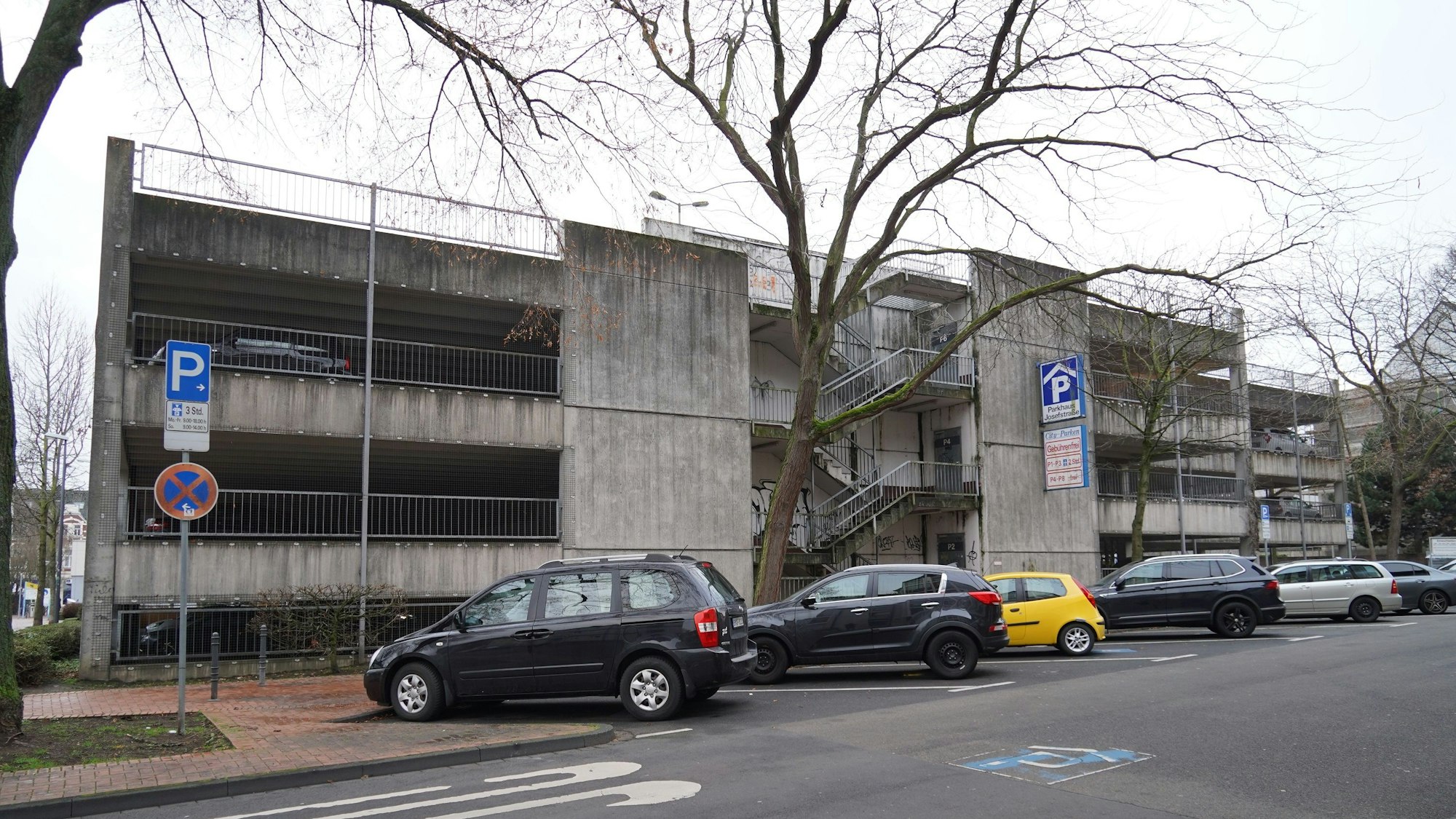Autos stehen auf Parkplätzen vor einem grauen Parkhaus
