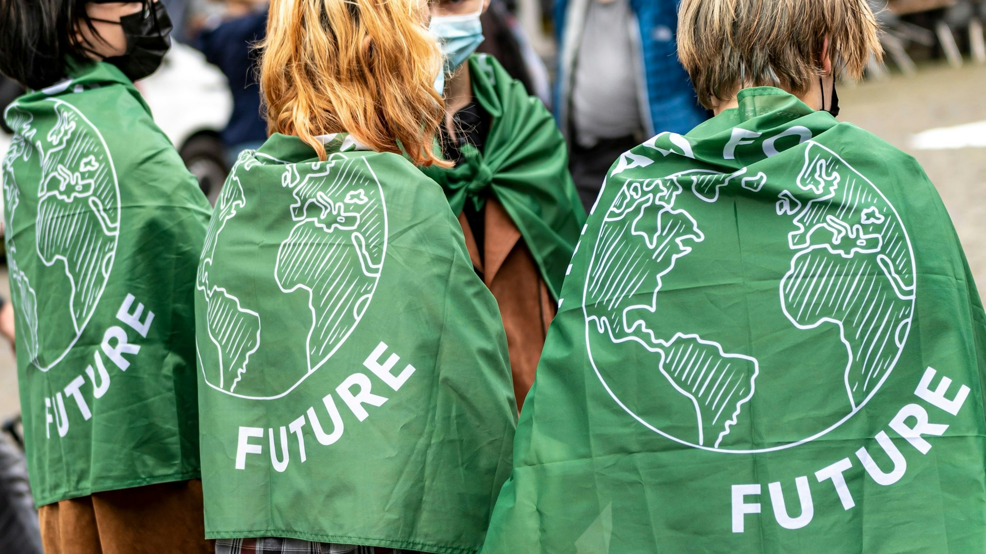 Drei Personen mit einer umgelegten Fridays-for-Future-Flagge