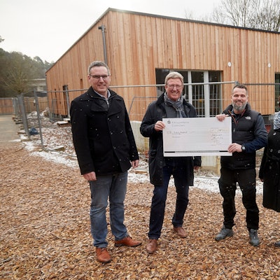 Mitglieder des Rotary-Club Euskirchen-Burgfey, Kindergartenleitung und der Bürgermeister stehen vor dem neuen Gebäude im Waldkindergarten.