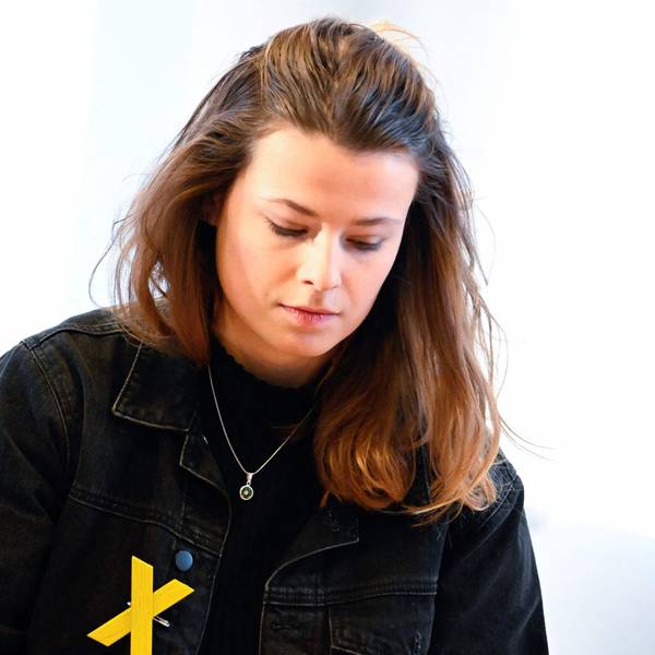 Die deutsche Klimaschutzaktivistin Luisa Neubauer vor einem Fenster. Auf ihrer schwarzen Jacke trägt sie ein gelbes X, um sich mit dem Widerstand gegen den Abriss des Braunkohledorfs Lützerath zu solidarisieren.