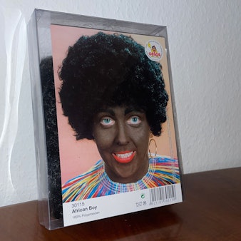 Eine Karnevalsperücke eines Kölner Kostümhändlers steht in der Kritik. Der Produktname „African Boy“ und die Beschminkung der Person haben eine rassistische Geschichte und bringen deshalb Empörung hervor.