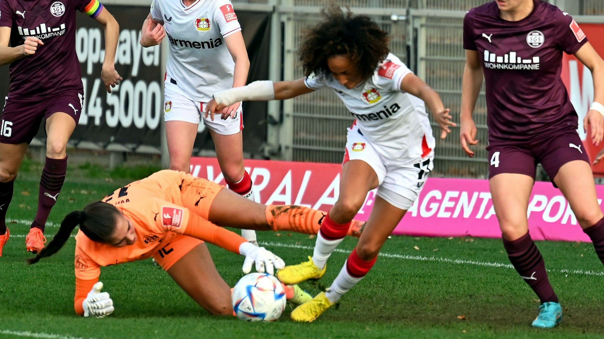 Eine Fußballerin befindet sich im Zweikampf mit der gegnerischen Torhüterin.