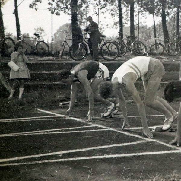 Athleten an der Startlinie auf einer Laufbahn. Das Bild ist in schwarz-weiß.