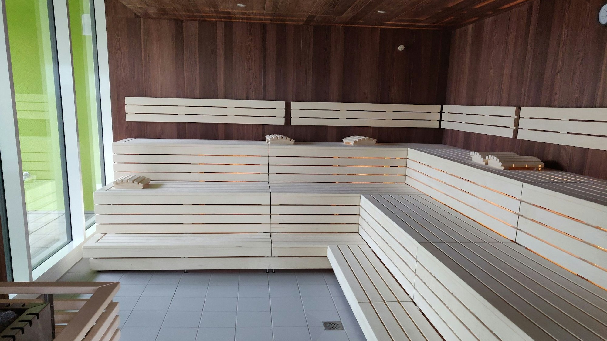 Blick in die Sauna mit weißen Holzbänke und dunkel vertäfelten Holzwänden.