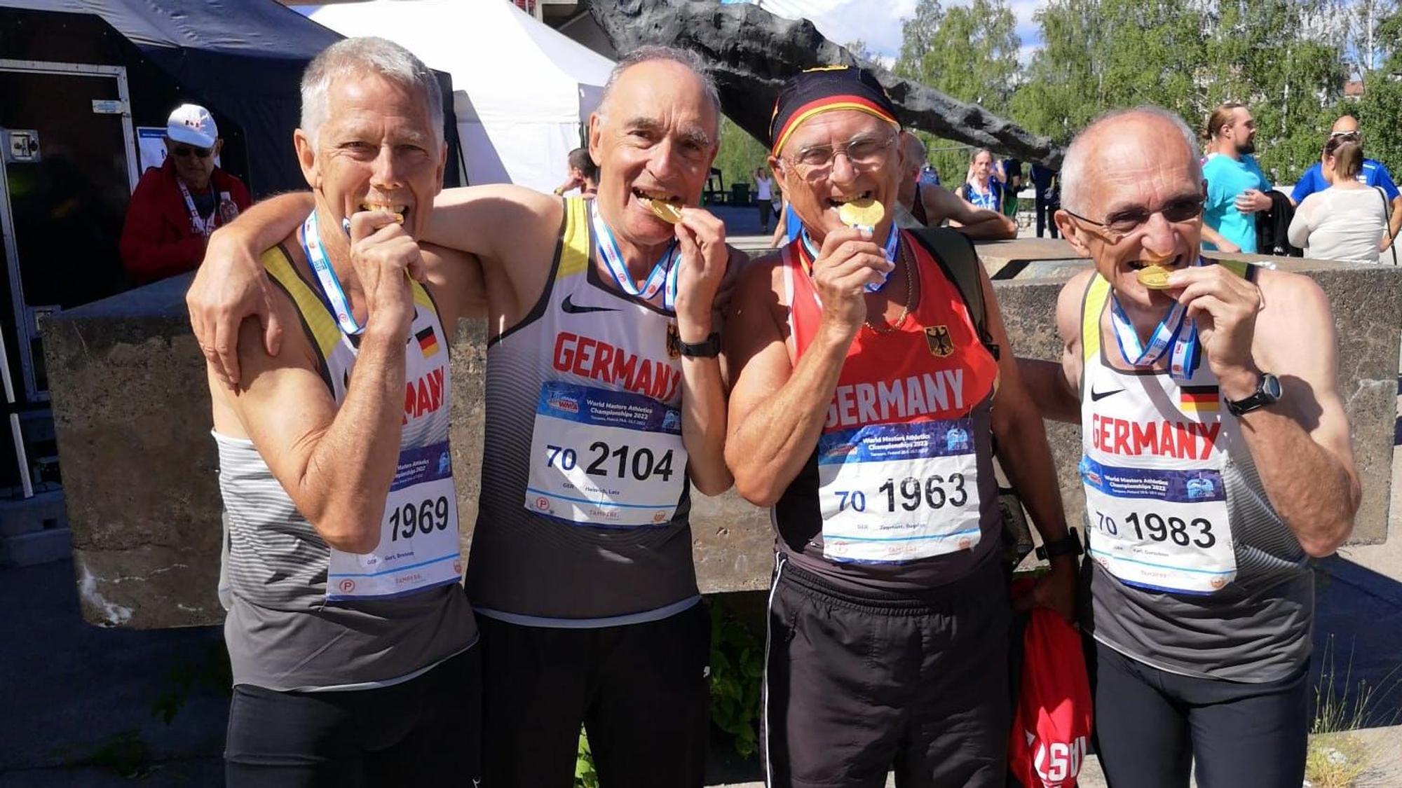 Die Sieger der 4x400-Meter-Staffel, darunter Heinrich Latz, beißen auf ihre Medaillen.