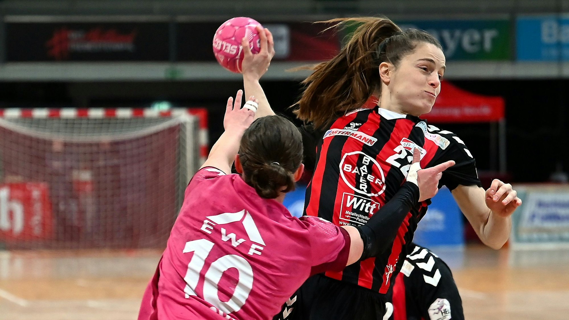 Eine Handballerin wird von ihrer Gegenspielerin beim Wurf bedrängt.