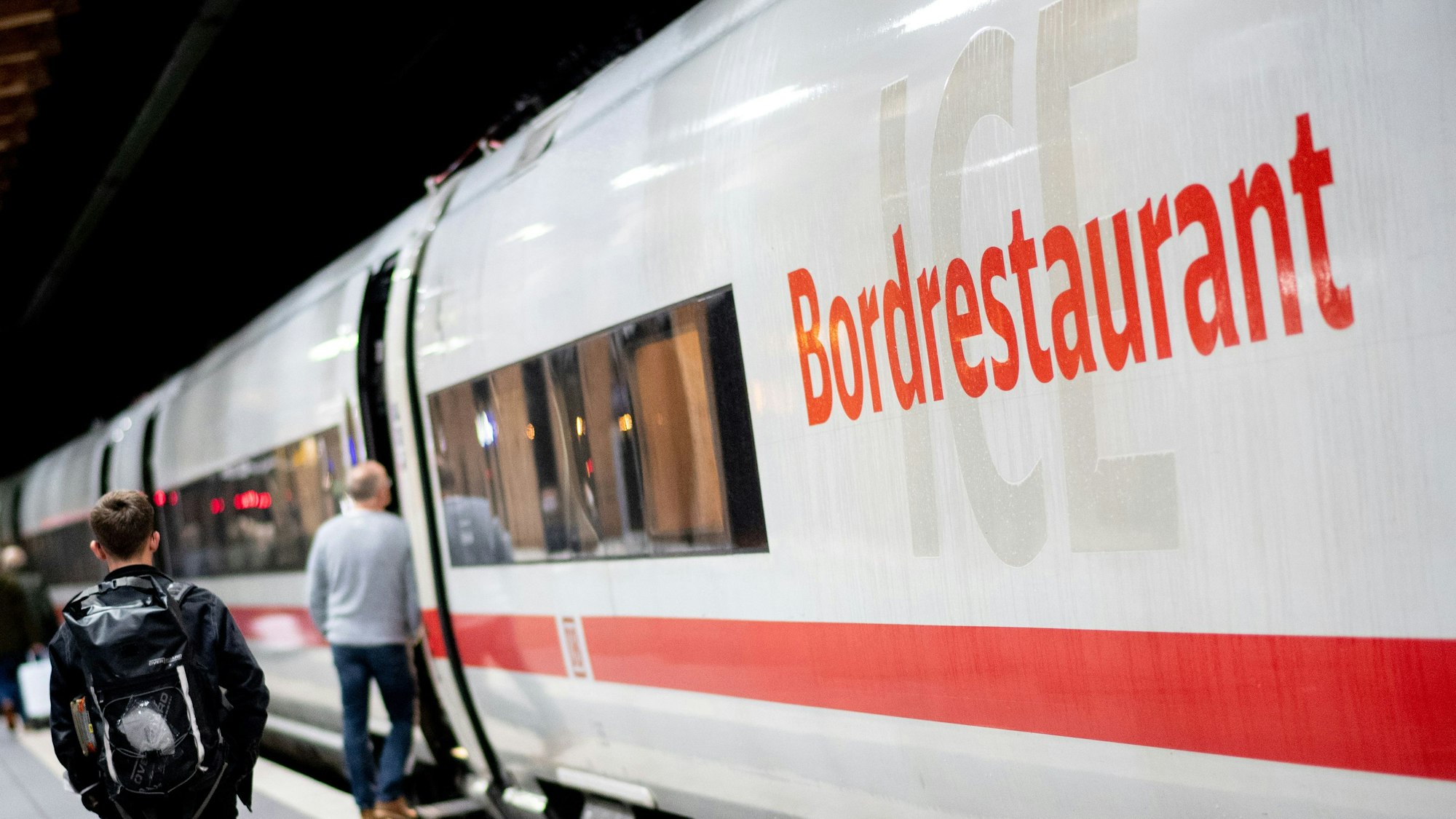 Fahrgäste gehen am frühen Morgen mit ihrem Gepäck über einen Bahnsteig am Hauptbahnhof, um in einen ICE der Deutschen Bahn (DB) einzusteigen.
