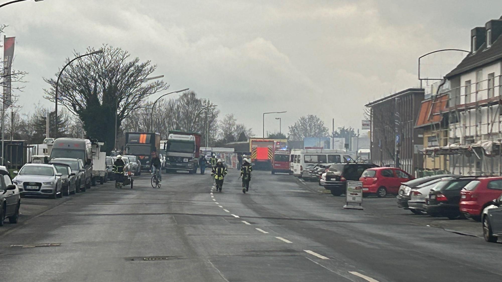 Mehrere Feuerwehrleute beim Einsatz auf der Straße.