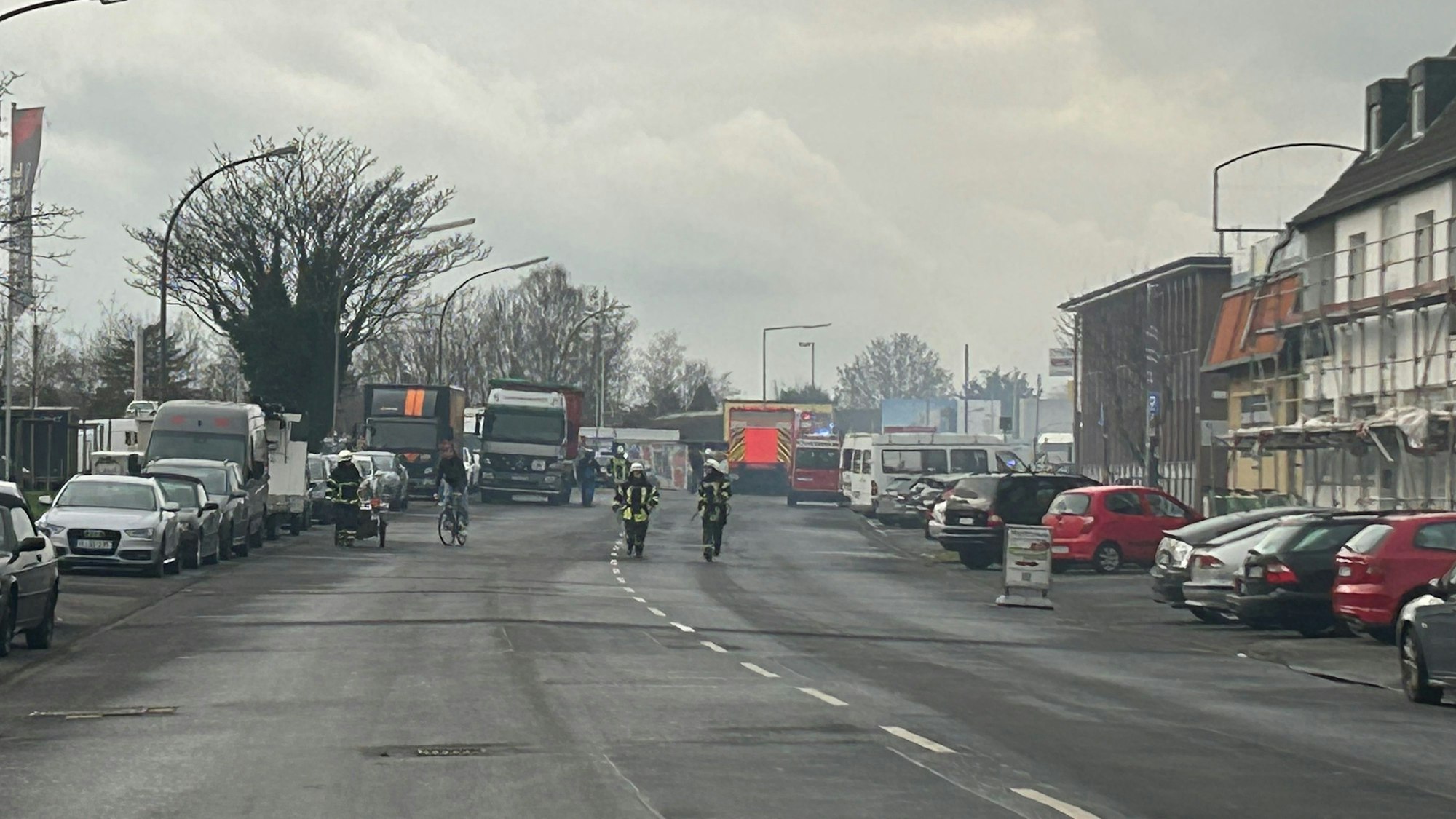 Mehrere Feuerwehrleute beim Einsatz auf der Straße.