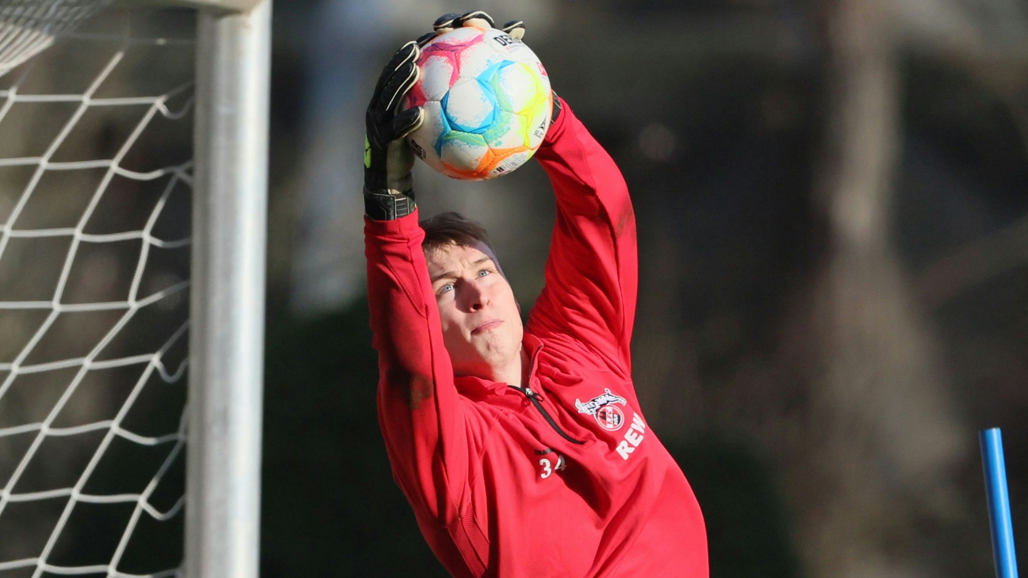 Ein Fußballtorwart fängt im Training einen Ball.