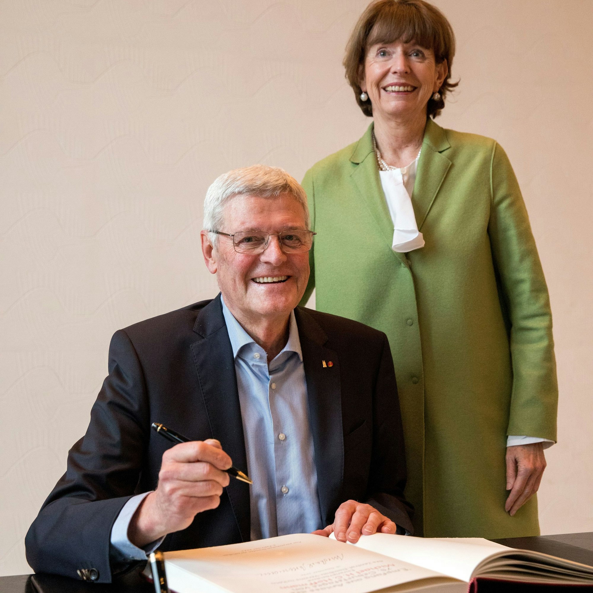 Michael H.G. Hoffmann trägt sich in das Gästebuch der Stadt Köln ein, Reker steht hinter ihm am Tisch.