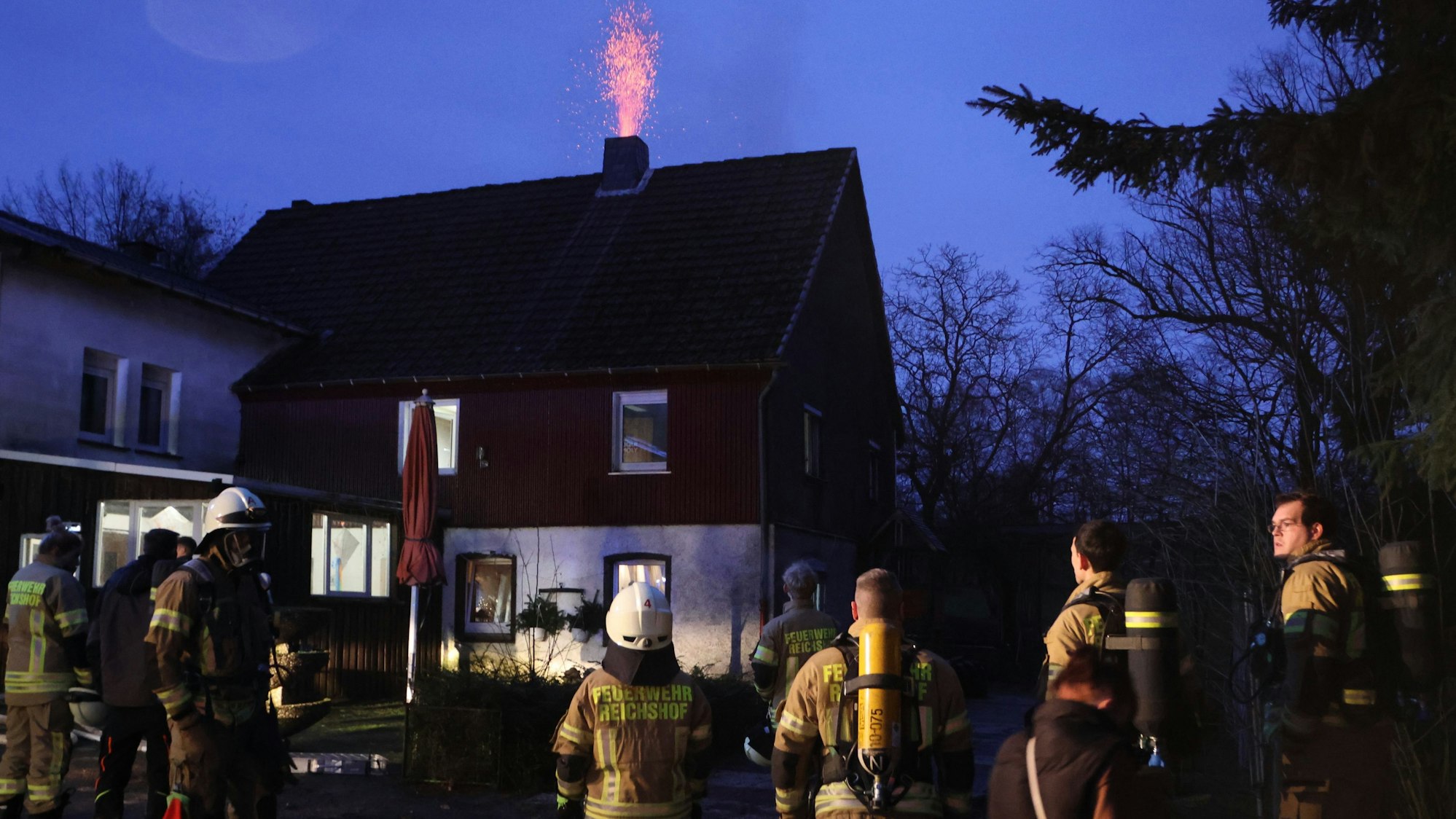 Einsatzkräfte der Freiwilligen Feuerwehr Reichshof stehen am späten Freitagnachmittag am Einsatzort.