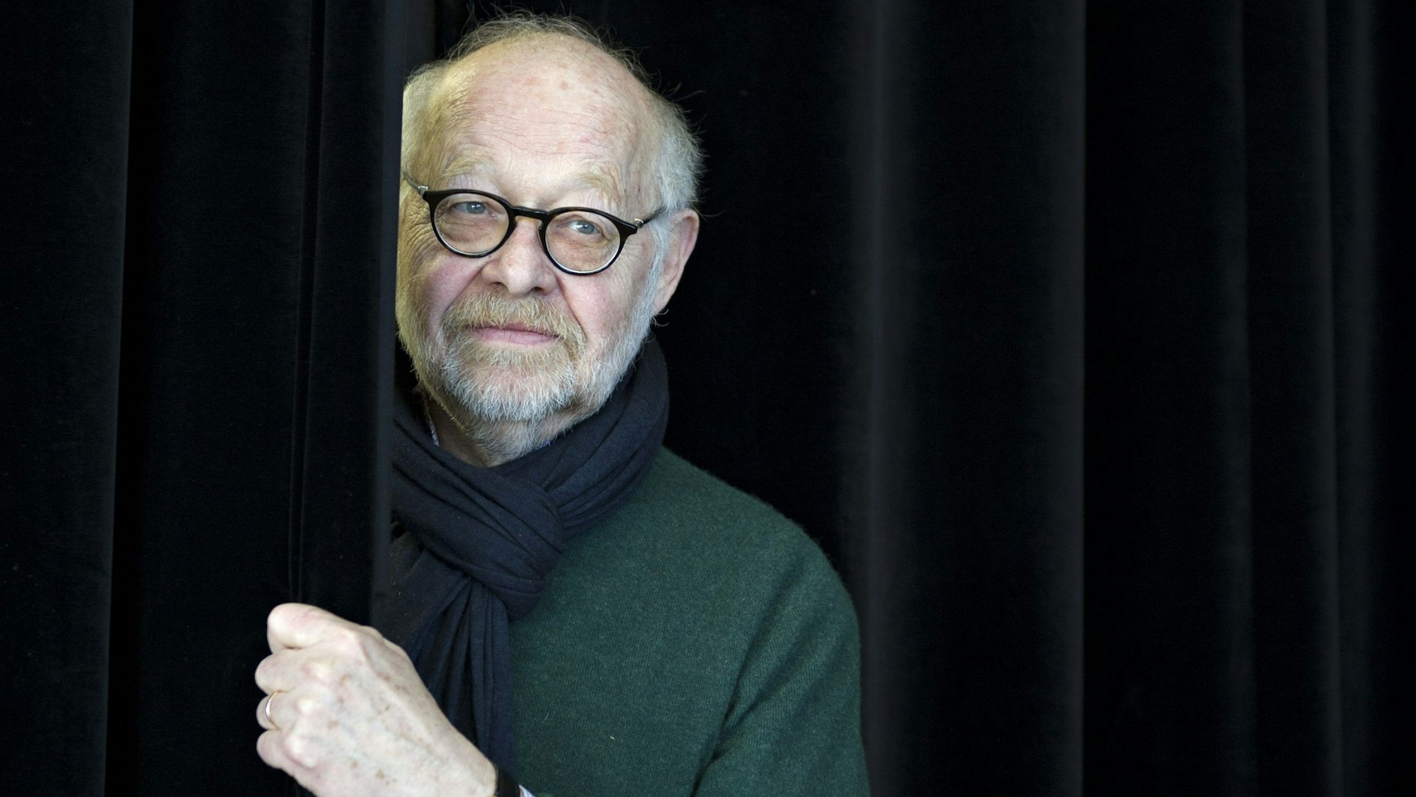 Jürgen Flimm, Intendant an der Staatsoper im Schiller Theater, posiert am 4. 3.2013 in Berlin am Rande einer Pressekonferenz mit einem schwarzen Vorhang.