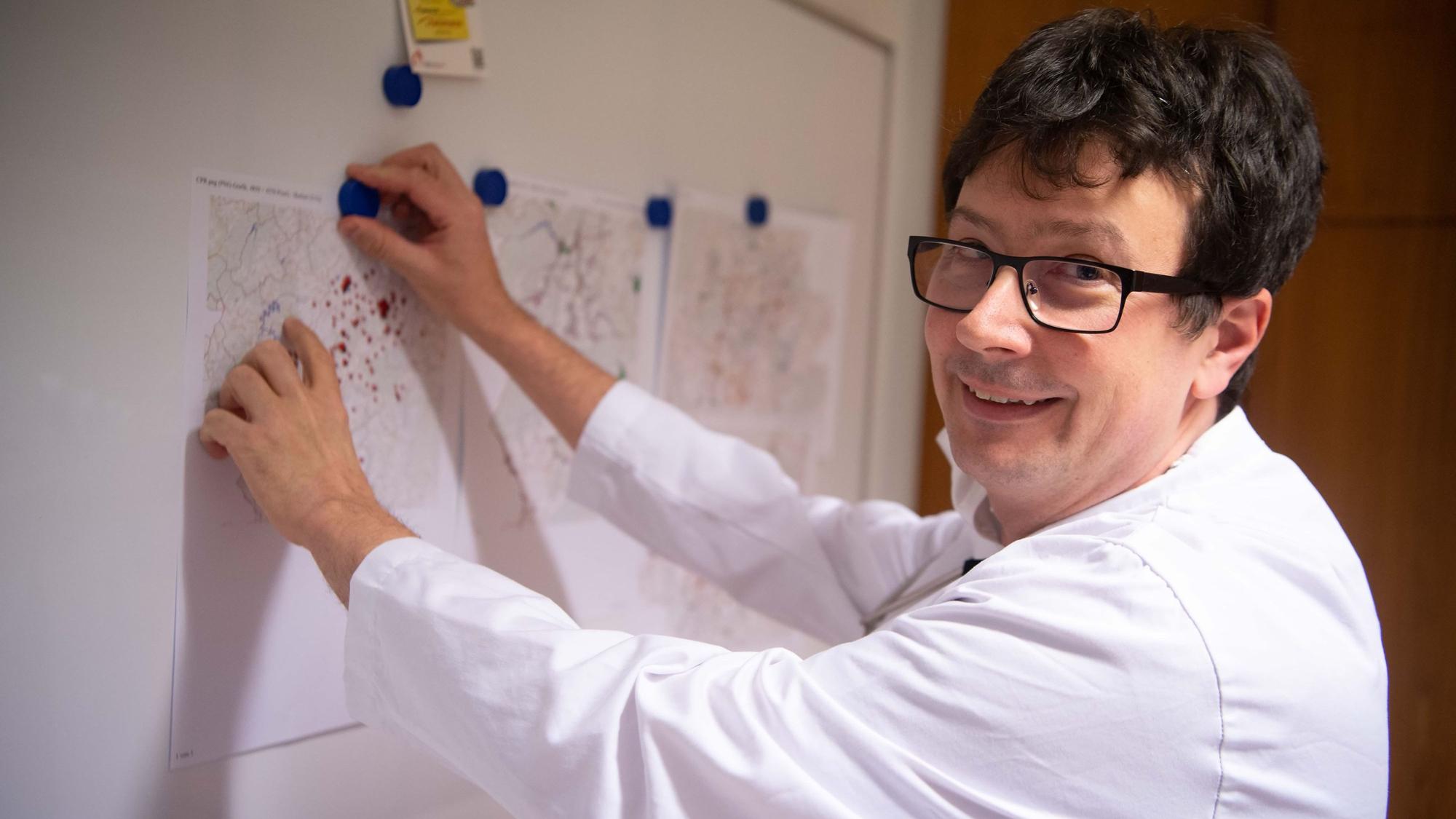 Dr. Jesko Priewe steht vor einer Magnetwand, an der Straßenkarten hängen.