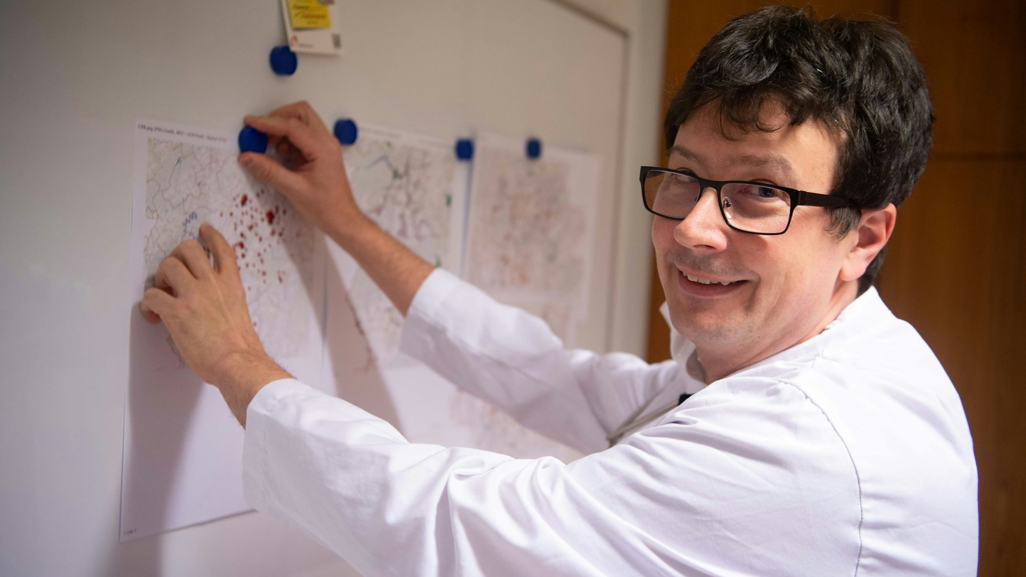 Dr. Jesko Priewe steht vor einer Magnetwand, an der Straßenkarten hängen.