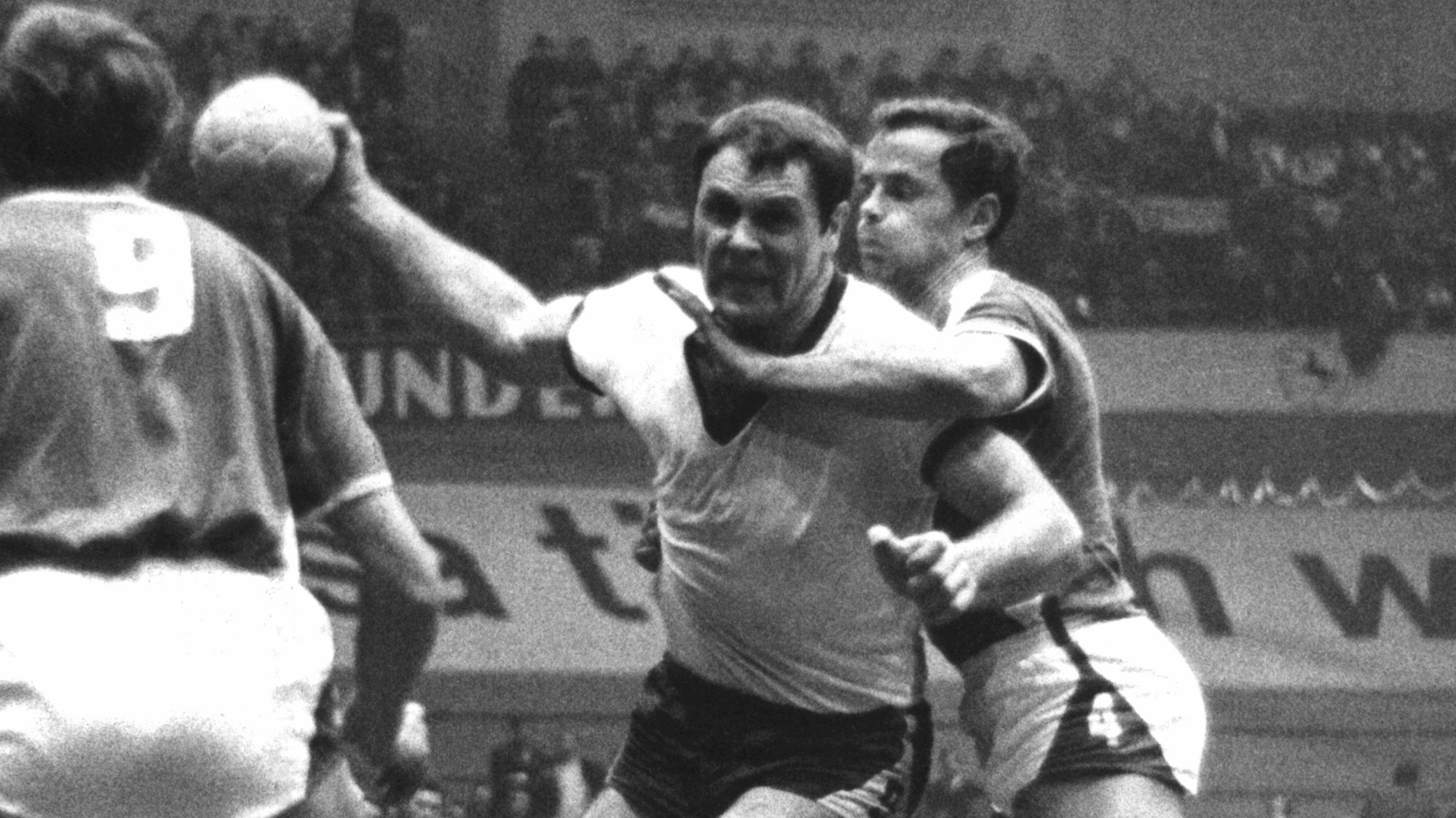 Auf einem alten Schwarz-Weiß-Foto sind zwei Handballer in einer Spielsituation zu sehen.