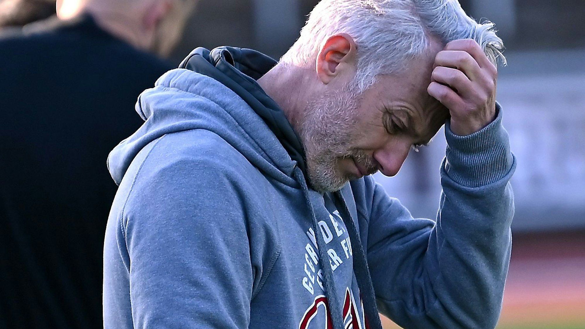 Ein Fußballtrainer kratzt sich nachdenklich am Kopf.