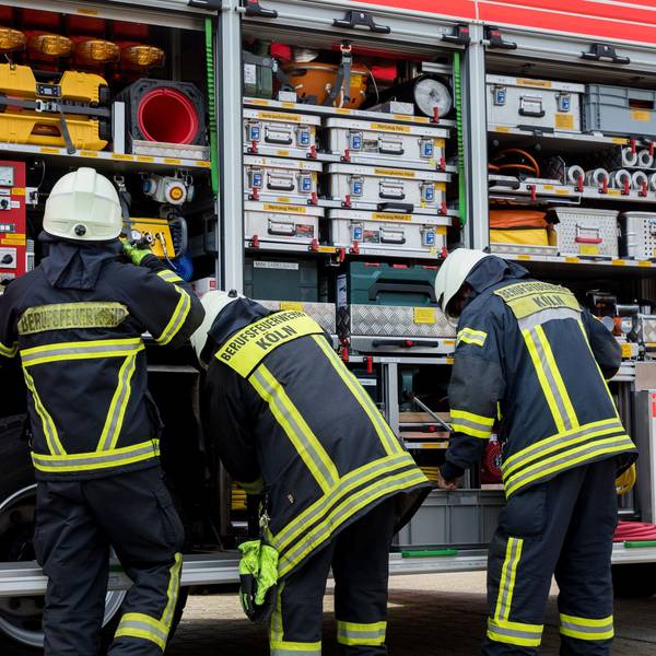 Drei Feuerwehrleute stehen vor ihrem Einsatzwagen.