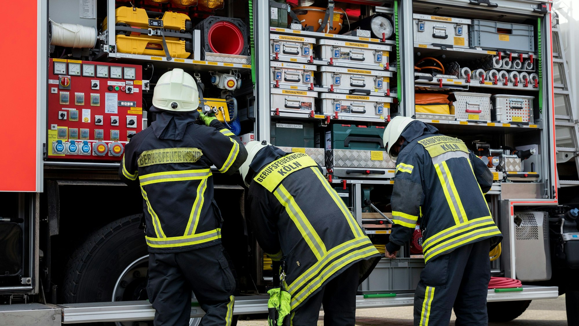 Drei Feuerwehrleute stehen vor ihrem Einsatzwagen.