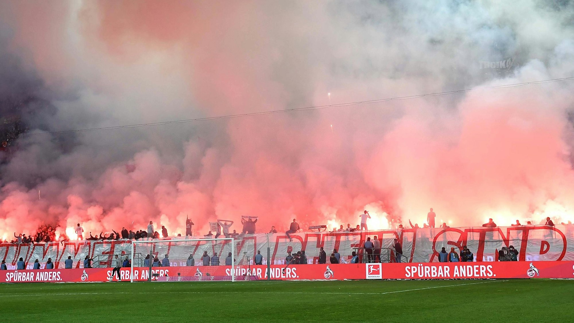 Vor dem Spiel des 1. FC Köln am 14. Spieltag gegen Bayer 04 Leverkusen haben Fans auf der Kölner Südtribüne massenhaft Pyrotechnik gezündet. Die Ränge sind in dichten Rauch gehüllt, die Fackeln leuchten gleißend rot.