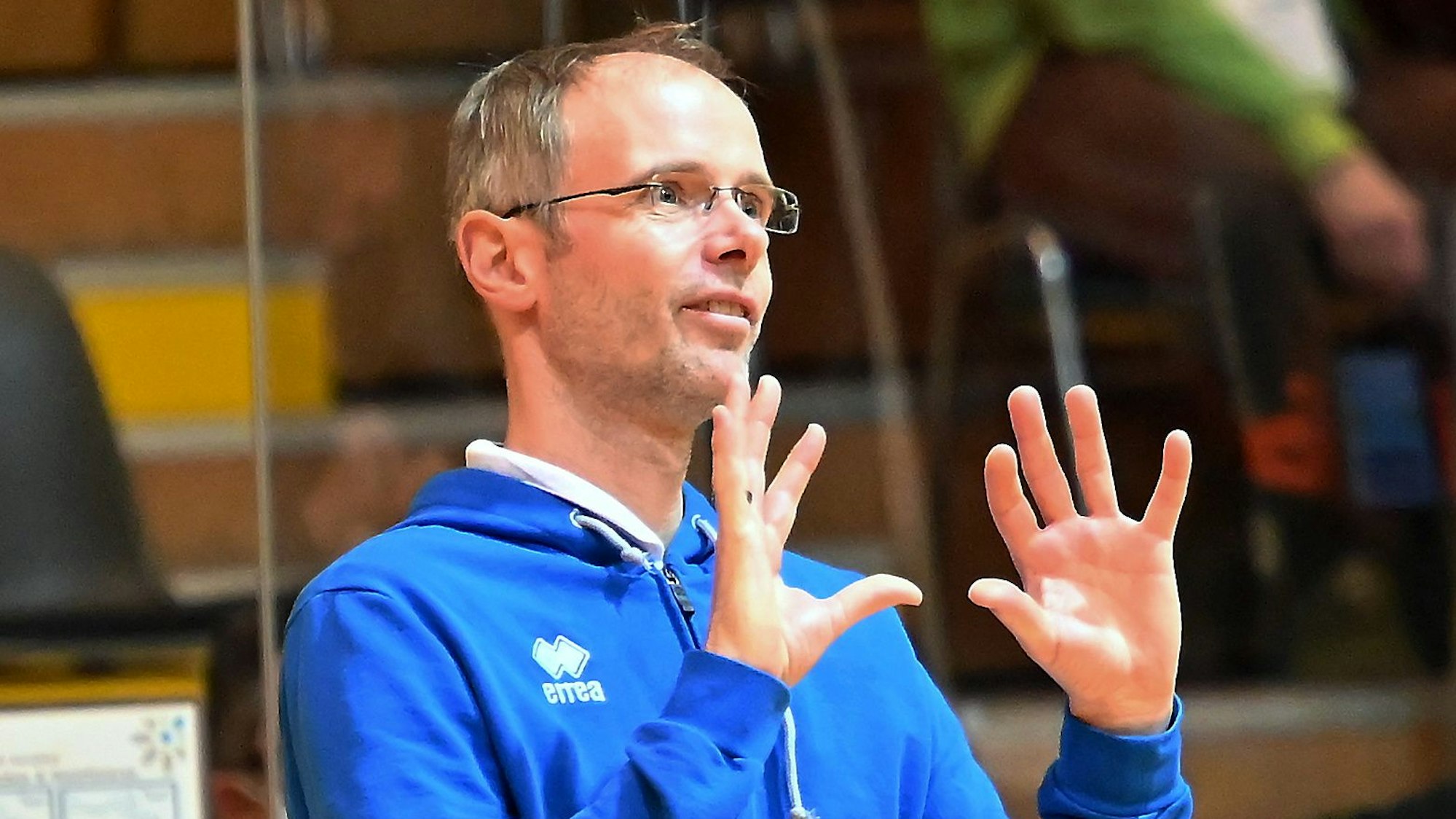 Ein Volleyballtrainer gestikuliert am Spielfeldrand.