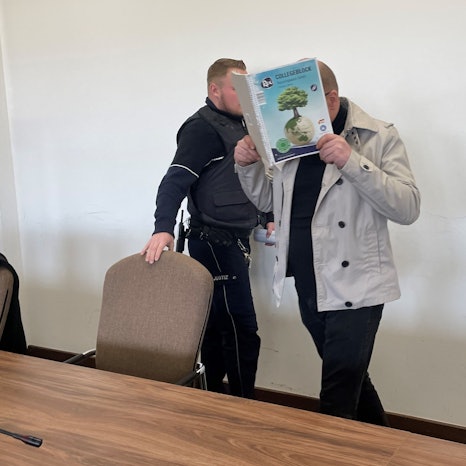 Der Angeklagte wird von einem Wachtmeister in Saal 112 des Kölner Landgerichts gebracht.