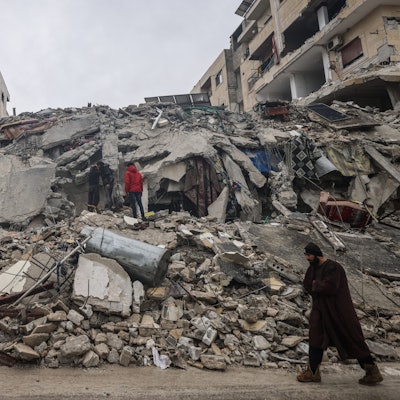 Menschen betrachten die Trümmer eines zerstörten Wohnhauses.